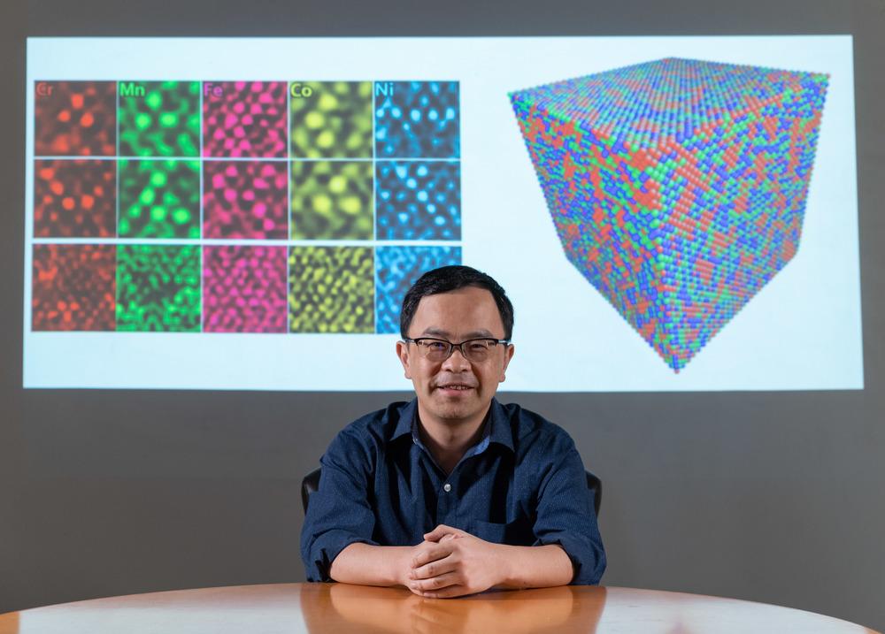 Ting Zhu, professor of mechanical engineering at Georgia Tech, in front of his TEM images of polycrystalline metals and a graphic simulating atomic structure. @ Georgia Institute of Technology