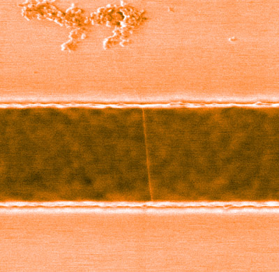 A carbon nanotube suspended across a trench in a silicon substrate. By developing a method that allows such suspended nanotubes to be functionalized with organic molecules, RIKEN researchers have enhanced their usefulness for sources of single photons. @ D. Kozawa et al.