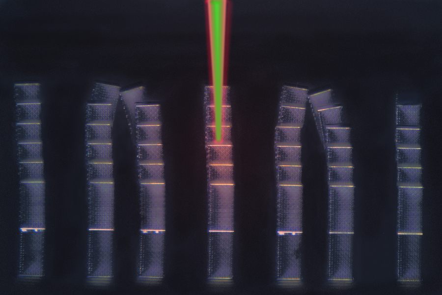 This optical micrograph shows an array of microscopic metamaterial samples on a reflective substrate. Laser pulses have been digitally added, depicting pump (red) and probe (green) pulses diagnosing a sample in the center. The LIRAS technique sweeps through all samples on the substrate within minutes. @ MIT