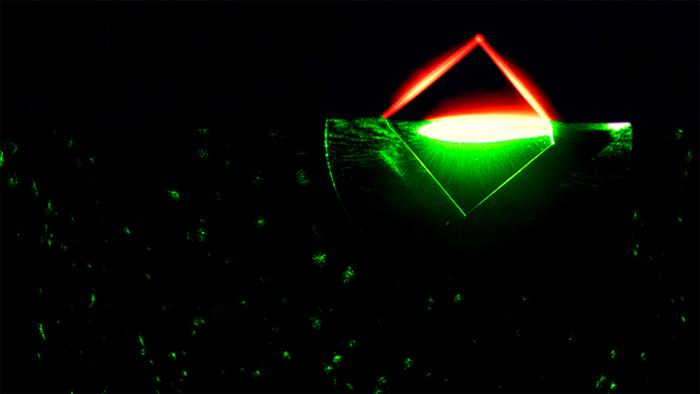 When a green laser shines on a special kind of diamond with atomic-scale defects, it can cause it to fluoresce red. This process is depicted in this photo of a quantum diamond sample as it was struck by the light of a green laser pointer, with a red light filter added to half of the sample to reveal the red fluorescence. @ Michael Livingston / PPPL Communications Department)