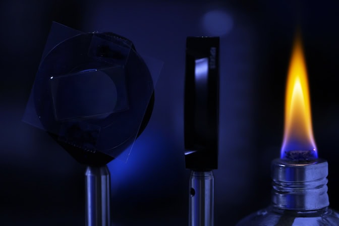 To measure how well the film twists light at high temperatures, U-M researchers use a small flame as a light and heat source. @ Brenda Ahearn, Michigan Engineering