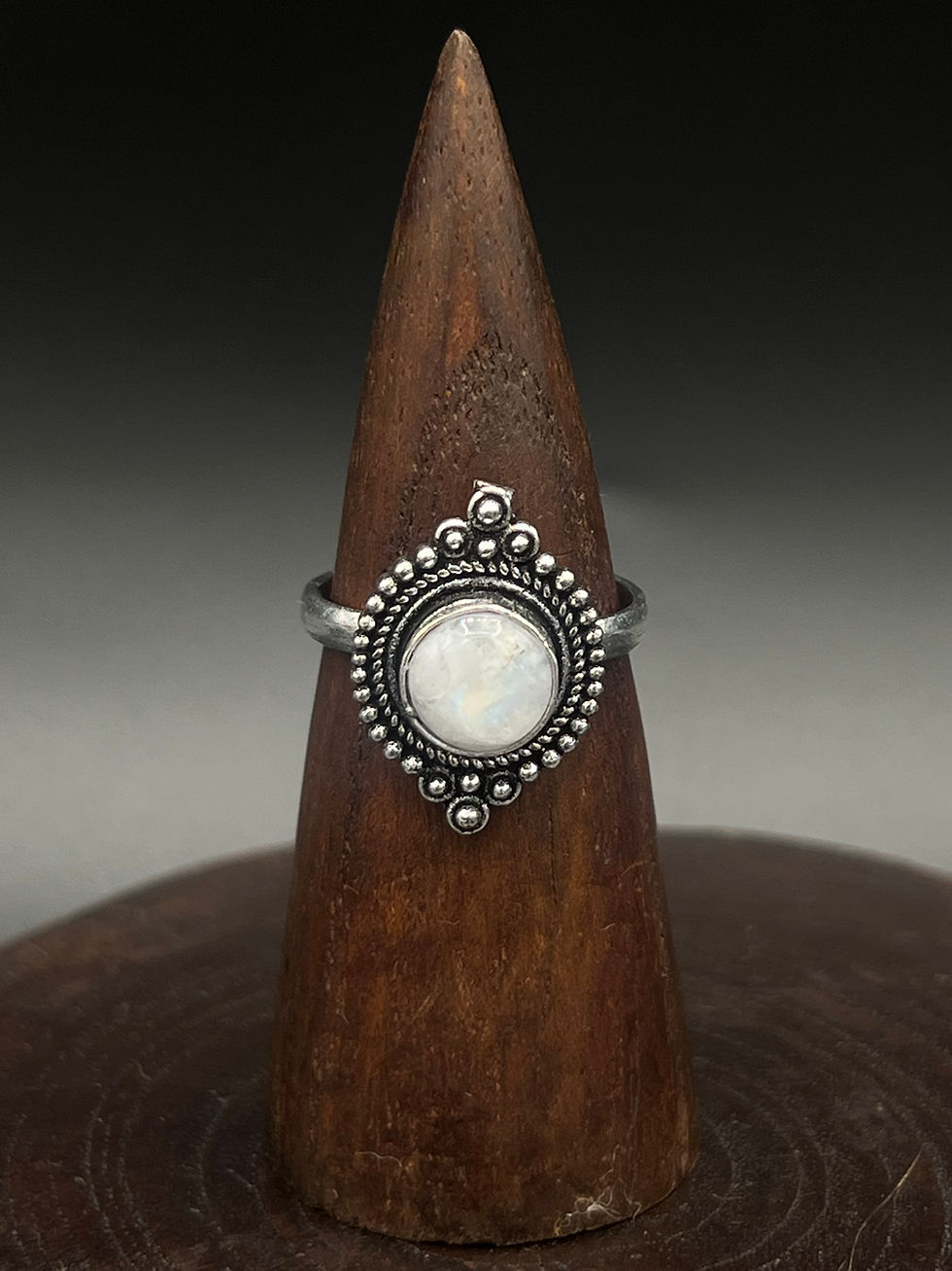 Silver ring with central black stone on wooden display