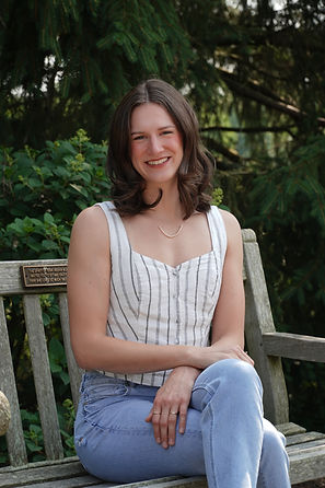 Hannah Pickerill smiles while relaxing on a wooden bench at House Of Athena Creative Retreats.