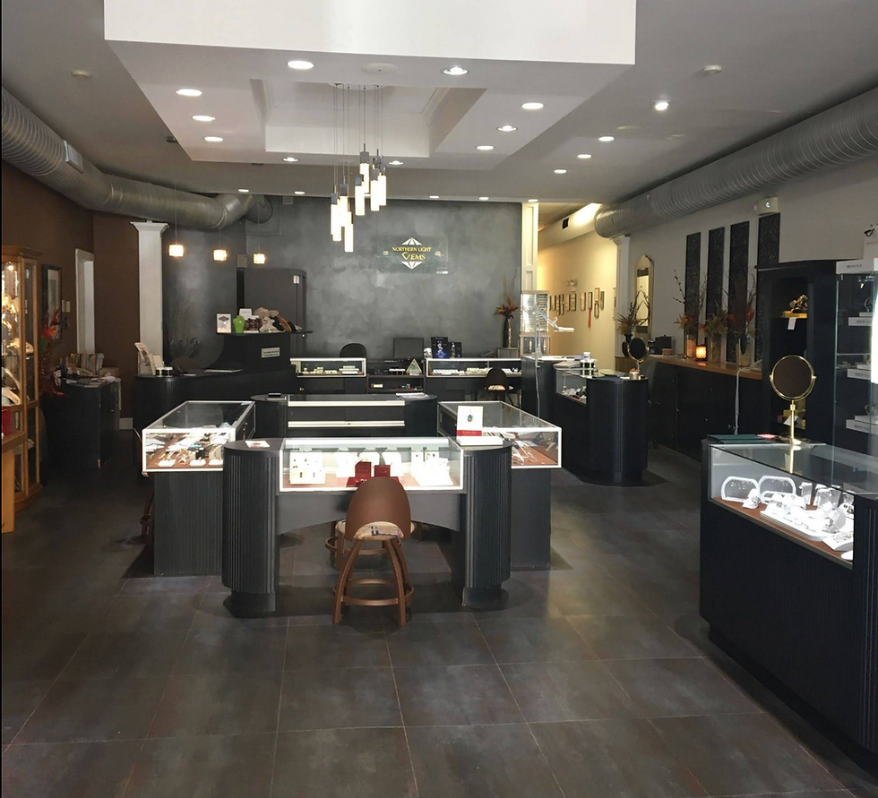 Wide shot of a contemporary jewelry store interior. The room has dark tile flooring, a mix of recessed and hanging pendant li
