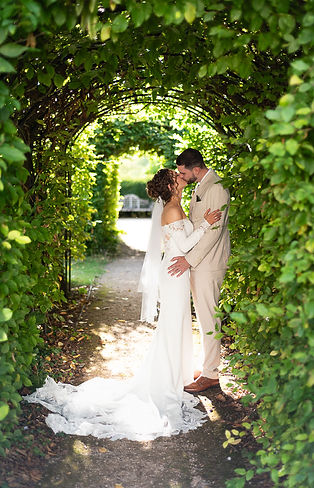 Bride and groom sharing an intimate kiss inside a green walk way with beautiful light coming through..JPG