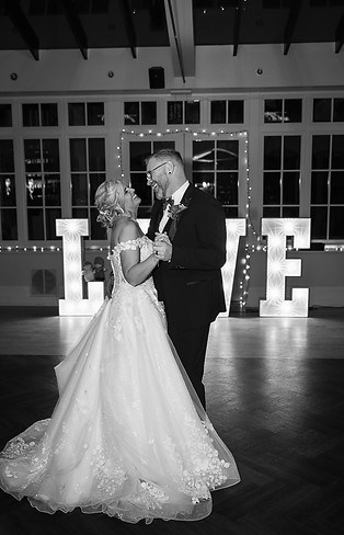 Bride and groom during their first dance, both smiling happily with a love sign in the background. Swynford Manor venue..JPG
