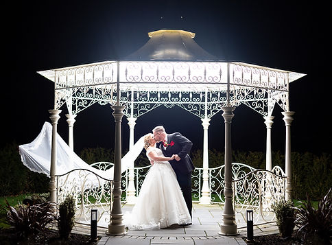Groom dipping bride for a kiss under a pergola, a light is making the pergola look amazing..JPG
