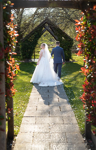 Bride and groom walking hand in hand, bride looking back over shoulder. Millbridge court wedding venue..JPG