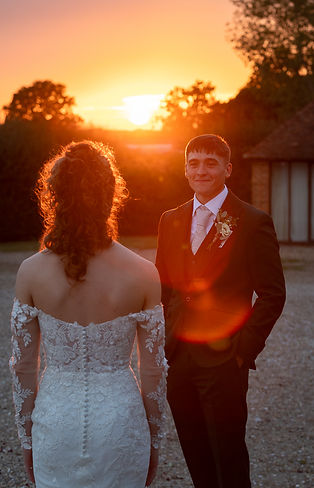 Groom looking towards bride, bride facing towards a beautiful sunset. Golden hour. Frasers coldharbour farm venue..JPG