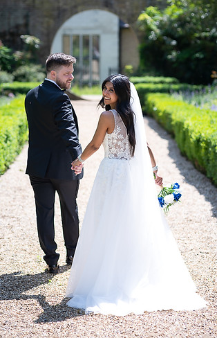 Bride and groom walking with bride looking over shoulder at Hanbury Manor wedding fair.JPG