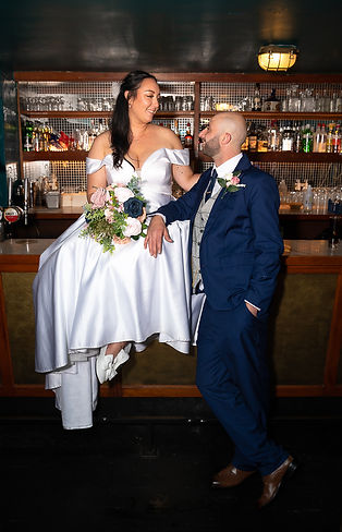 Bride sat on top of a bar with her hand on grooms shoulder and his hand is on her leg. .JPG