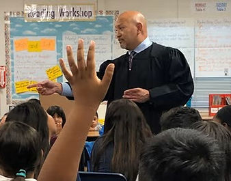 A judge standing in a classroom wearing a black robe