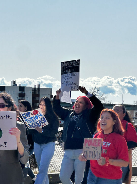 People protest, holding signs: "Stop tuition increase", "Power in the people".