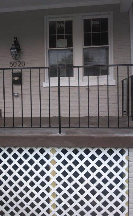 Residential front porch with white lattice and black railing