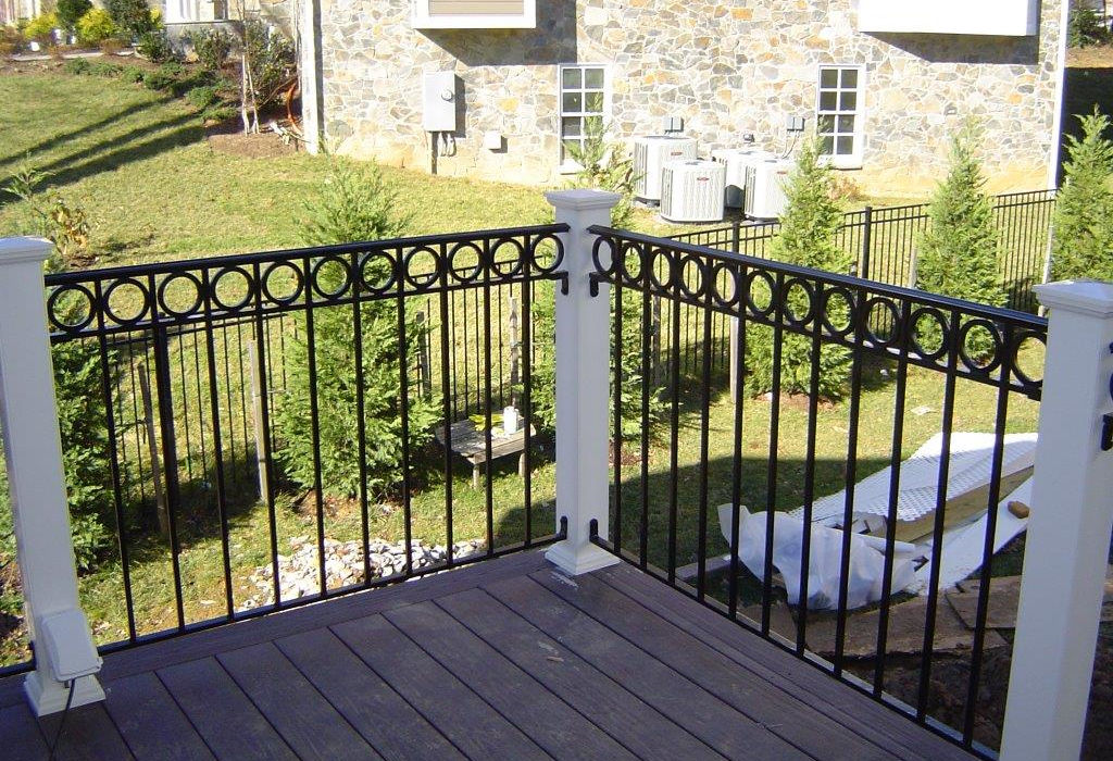 Deck with black iron railing overlooking a backyard