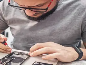 Wireless dealer diagnosing a phone that will not power on using a known-good charger and a multimeter at a repair bench