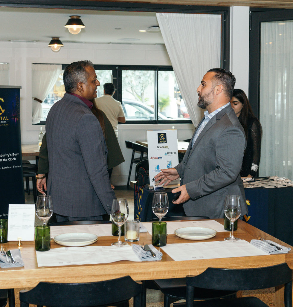 Two men in suits talking at a restaurant.
