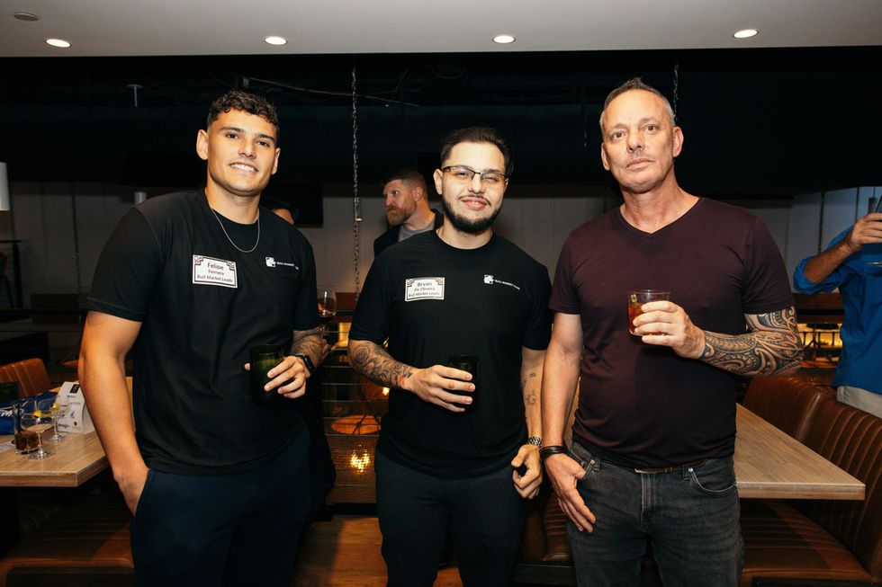 Three people holding drinks at a social event.