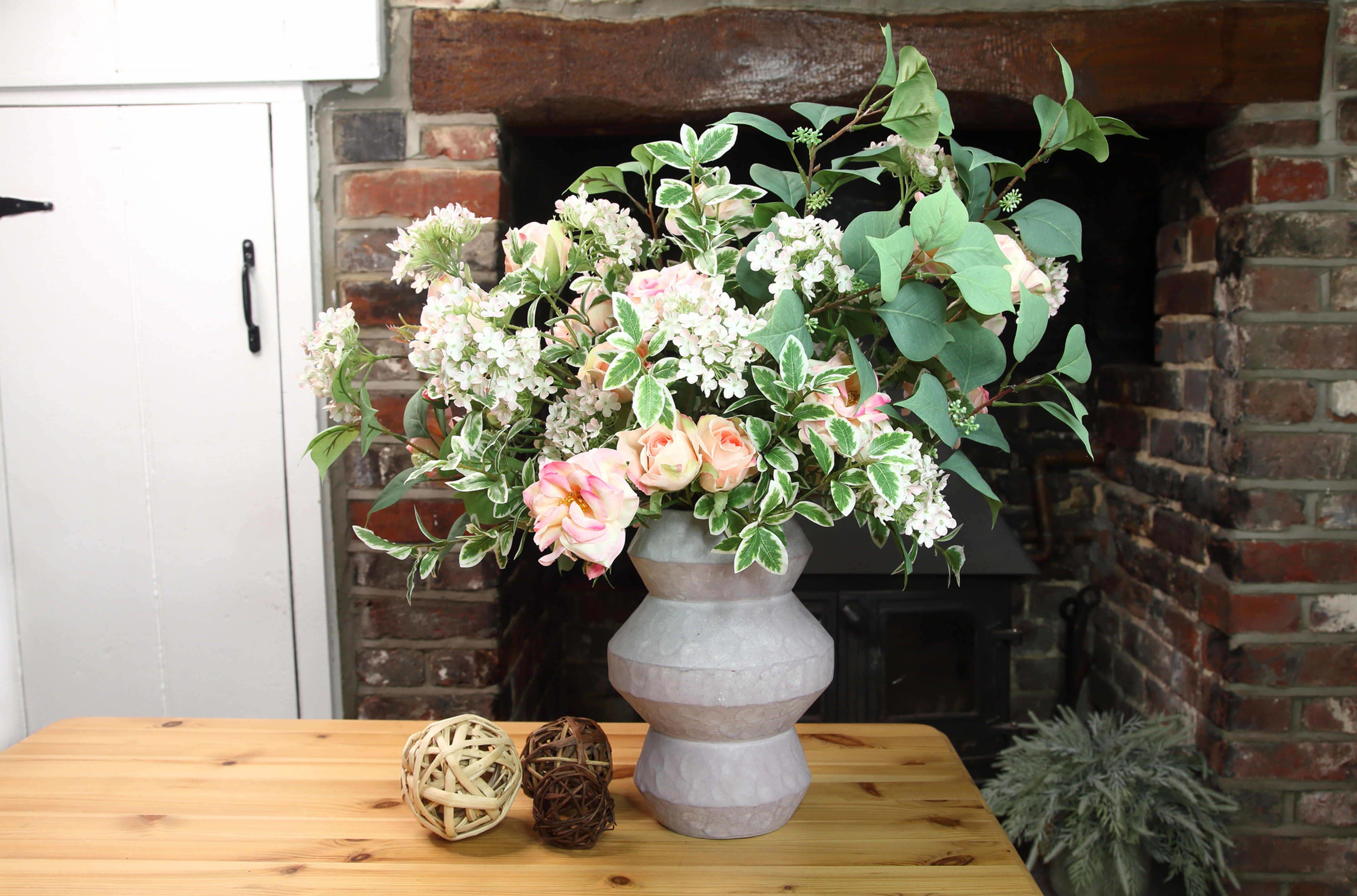 Roses, mini hydrangea and mixed foliage in a dimpled matt grey ceramic vase