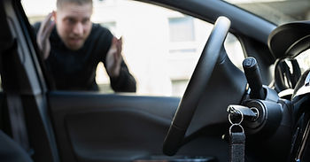 man locked out of his car looking through the window