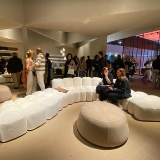 Designová modulární sedačka s měkkými zaoblenými tvary, obklopená návštěvníky veletrhu.