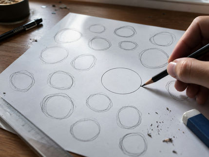 A hand drawing rows of practice circles in pencil, one clean among many rough ones, illustrating the Eight of Pentacles tarot card meaning of daily practice