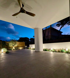 Covered terrace area of a modern villa illuminated at night in Roche