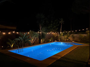 Illuminated swimming pool at night with garden in Urbanización Roche