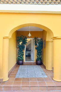 Arched entryway with soft shade leading into an Andalusian home near the Atlantic.
