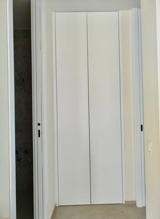 Closed white full-height doors hiding the service cabinet in hallway of Roche house. Ref 34