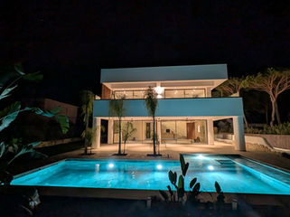 Full frontal night view of villa and pool.