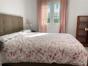 Comfortable bedroom with patterned bedding and soft curtains.