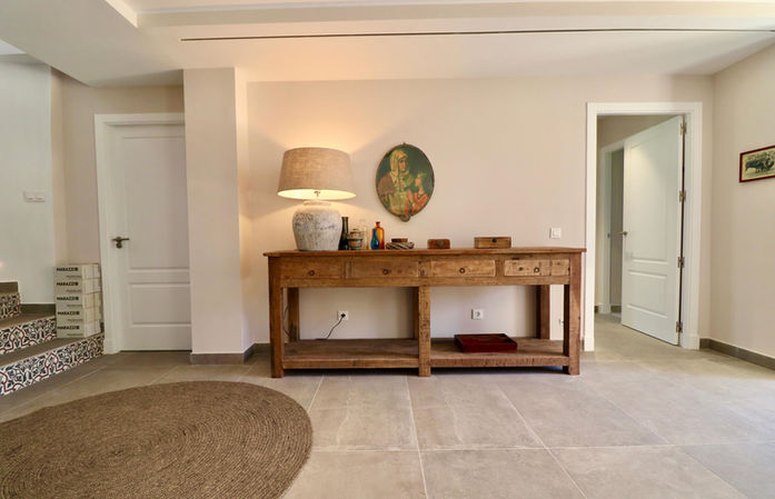 Hallway with wooden console table and round carpet.