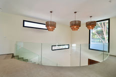 Upper floor view showing staircase with glass balustrade and decorative ceiling lights.