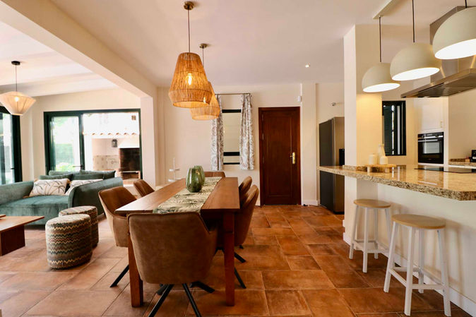 Dining table with warm lighting and view into the kitchen.