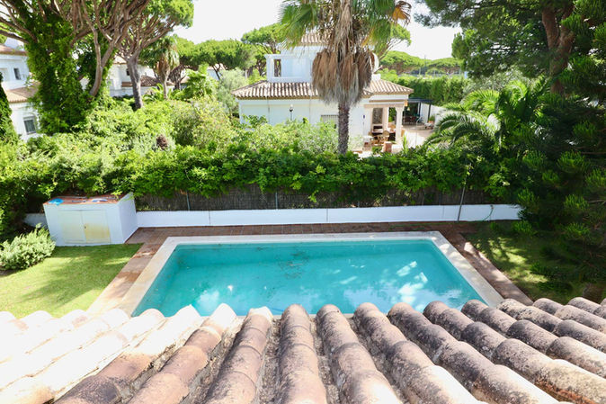 Elevated perspective of turquoise pool and palm trees in Roche residential area.