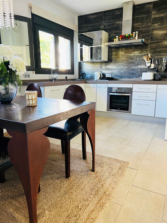 White kitchen with dark backsplash and dining area.