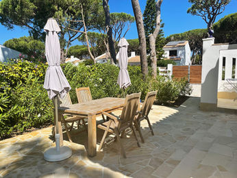 Outdoor dining terrace with wooden table and umbrellas.