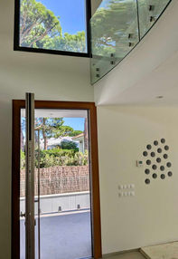 Modern entrance hall with natural light, glass balustrade and elegant design details in Roche, Andalusia.