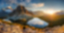 A sunny fall day in the Canadian Rockies with snowy mountain peaks and reflective lakes.