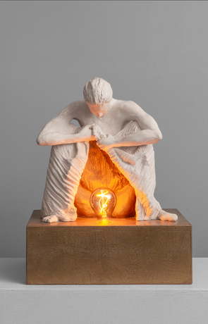 Sculpture d'une femme accroupie, relevant sa robe pour révéler une lampe, représentation de la naissance
