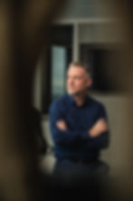 Christian Becker schaut mit verschränkten Armen links an der Kamera vorbei nach draußen