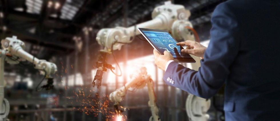 Imagem de um executivo controlando robôs na linha de montagem de uma fábrica. Ele está de costas e manuseia um tablet.