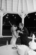 black and white photo of groom feeding the bride cake while they both laugh