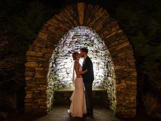 a bride and groom kiss while backlit in a stone arch in Fernhill House Hotel