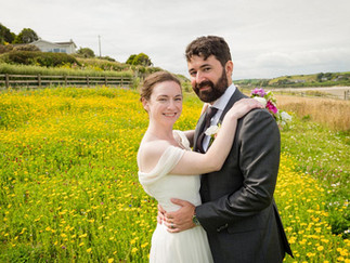 a bride and groom embrace in a field of yellow flowers