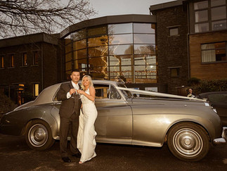 a bride and groom stand beside their vintage wedding car at the Kinsale Hotel and Spa