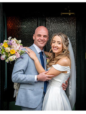 a bride and groom smile and embrace in a doorway in clonakilty, cork