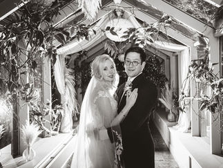 a bride and groom embrace in a backlit glass corridor