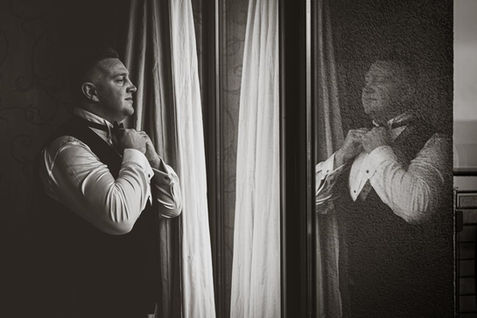 a groom is reflected in a window
